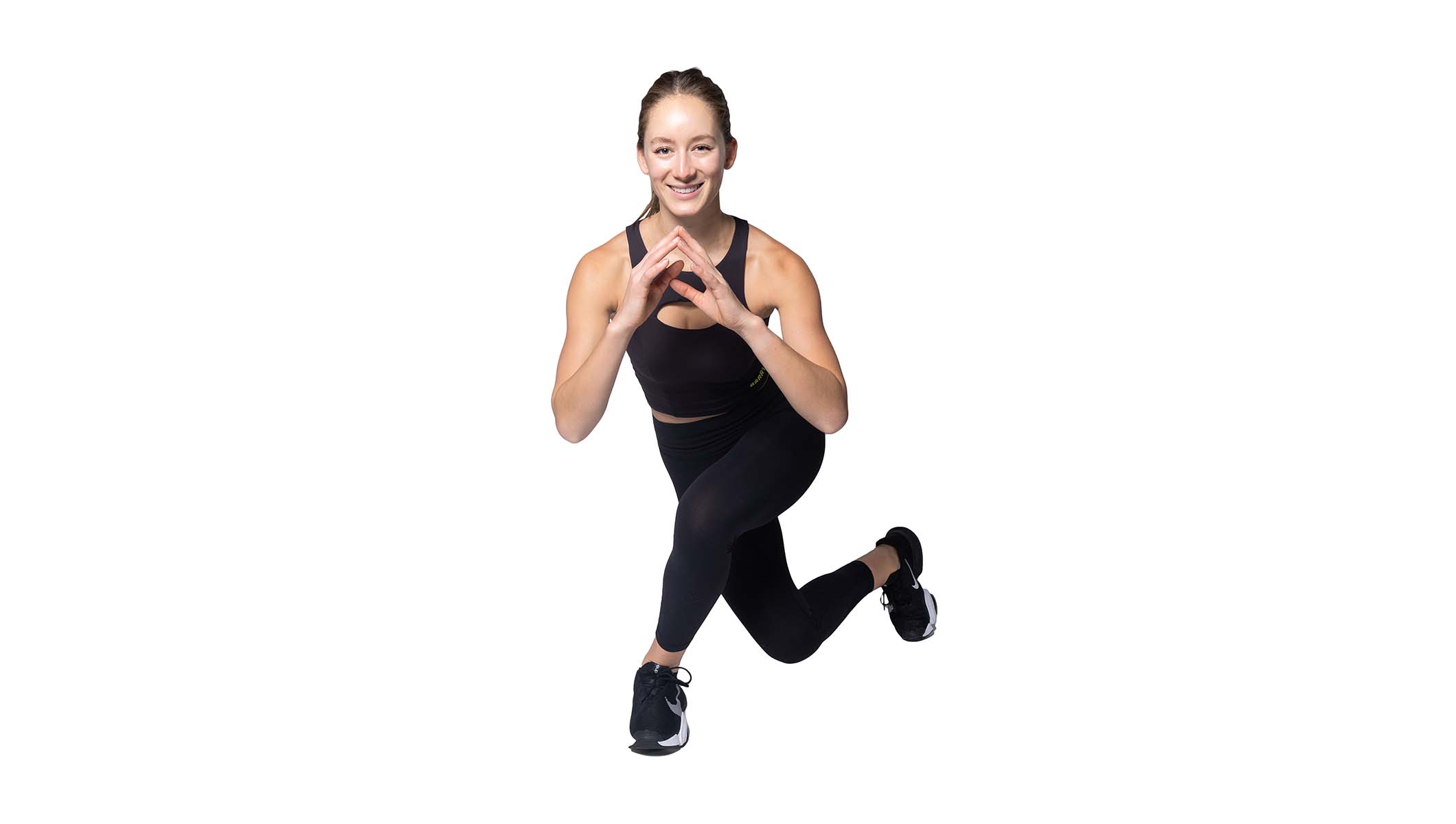 Barry’s instructor wearing a black top in a lunge smiling against a white background