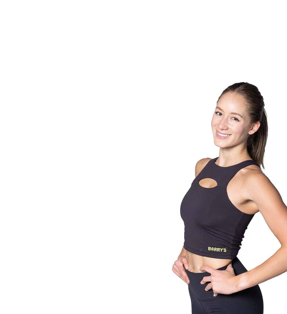 Barry’s instructor wearing a black top standing confidently smiling against a white background