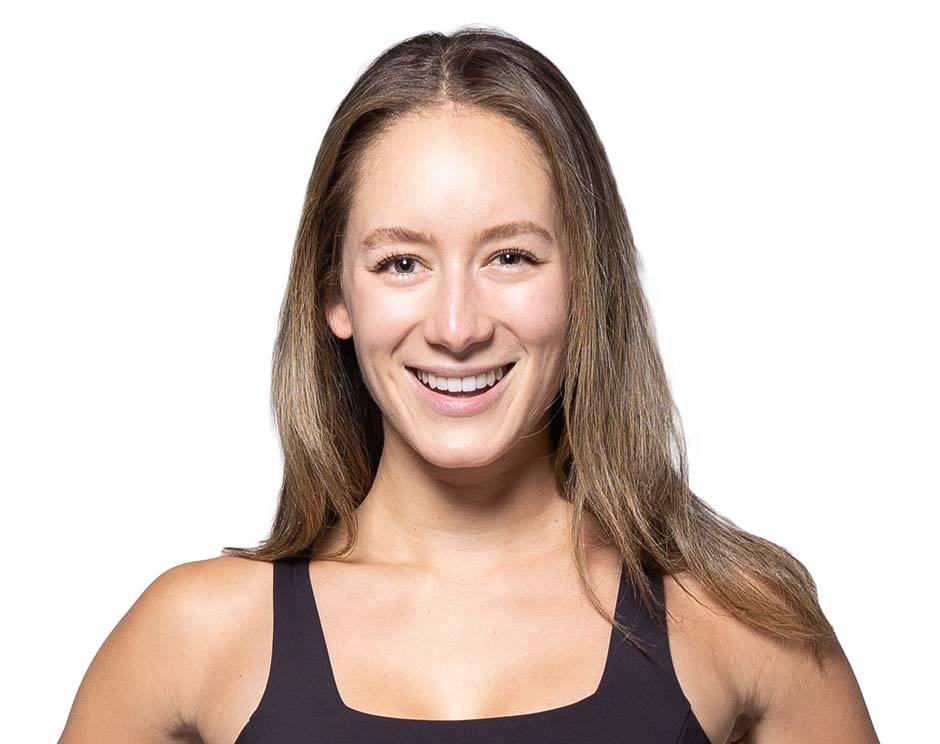 Barry’s instructor wearing a black top standing confidently smiling against a white background