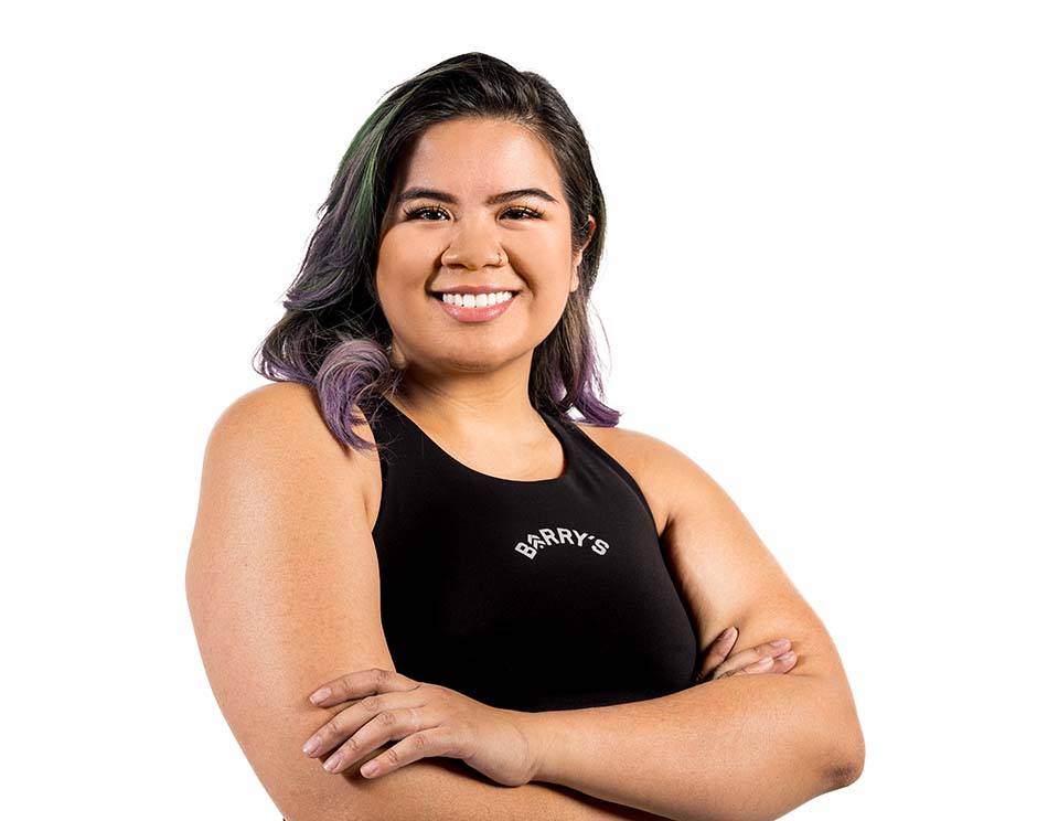 Barry’s instructor wearing a black top standing confidently smiling against a white background