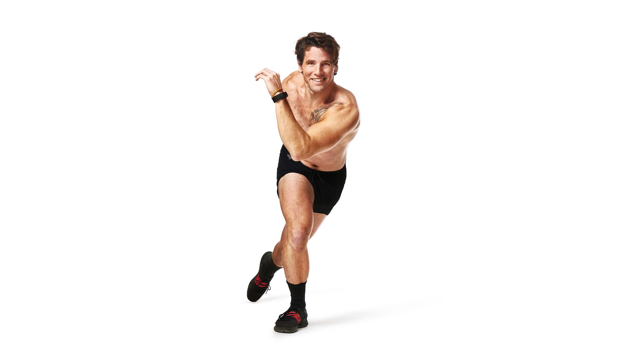 Barry’s instructor shirtless in a runner position smiling against a white background