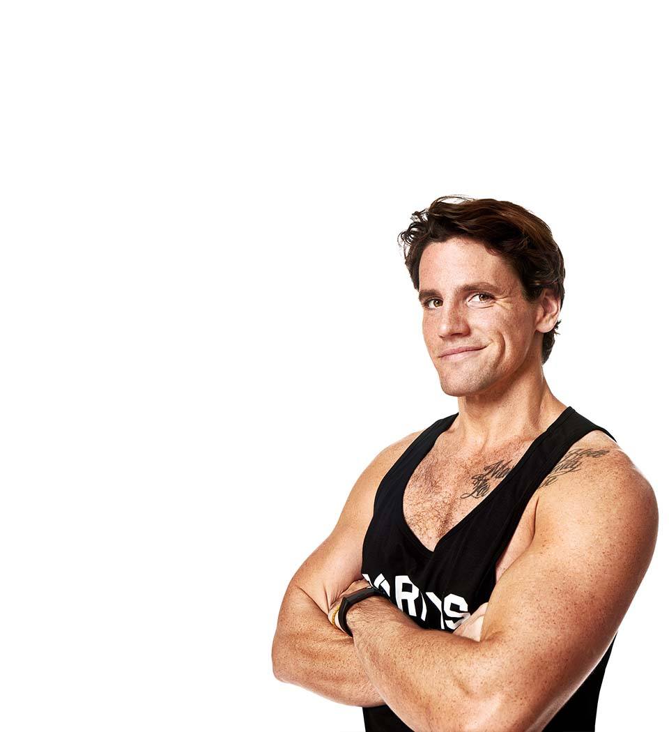 Barry’s instructor wearing a black top standing confidently smiling against a white background