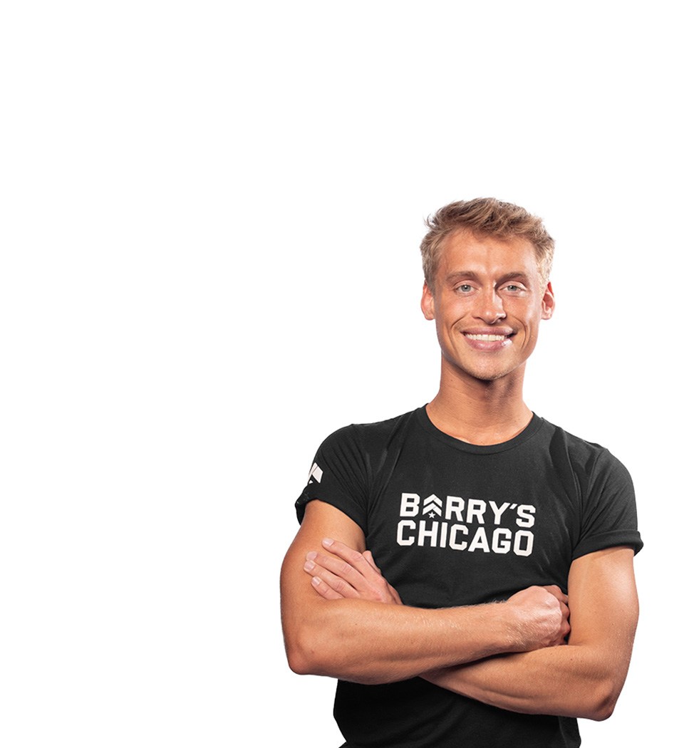 Barry’s instructor wearing a black top standing confidently smiling against a white background