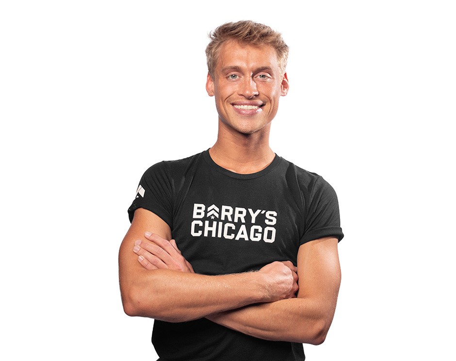 Barry’s instructor wearing a black top standing confidently smiling against a white background