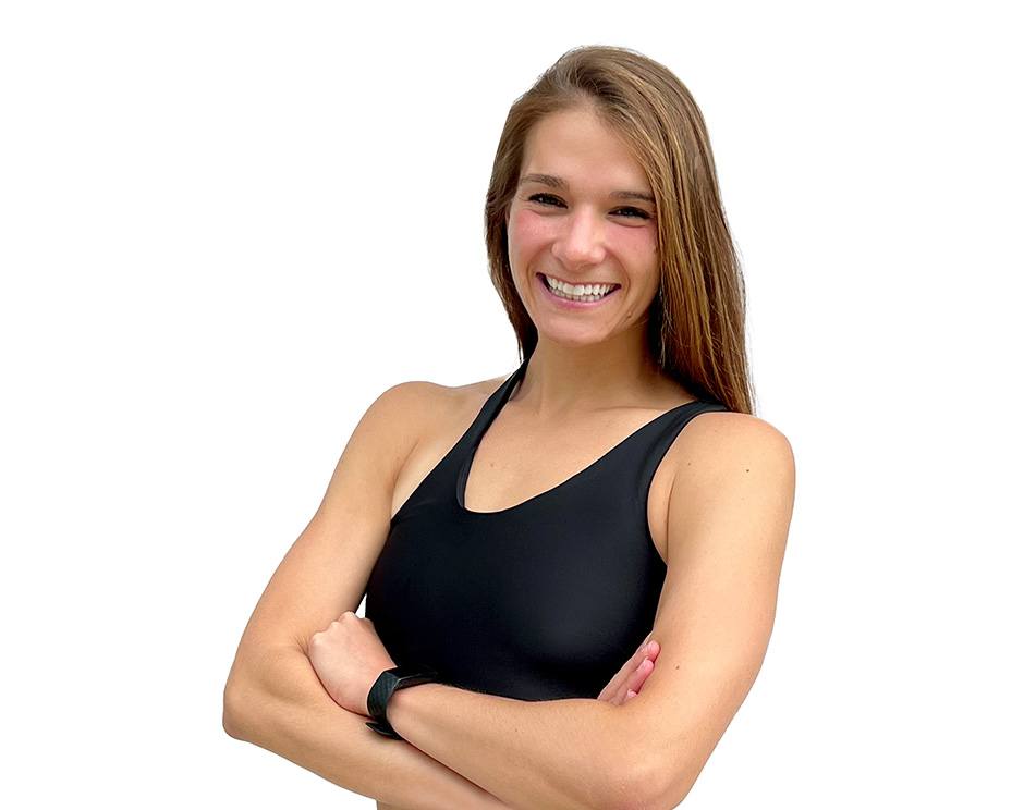 Barry’s instructor wearing a black top standing confidently smiling against a white background