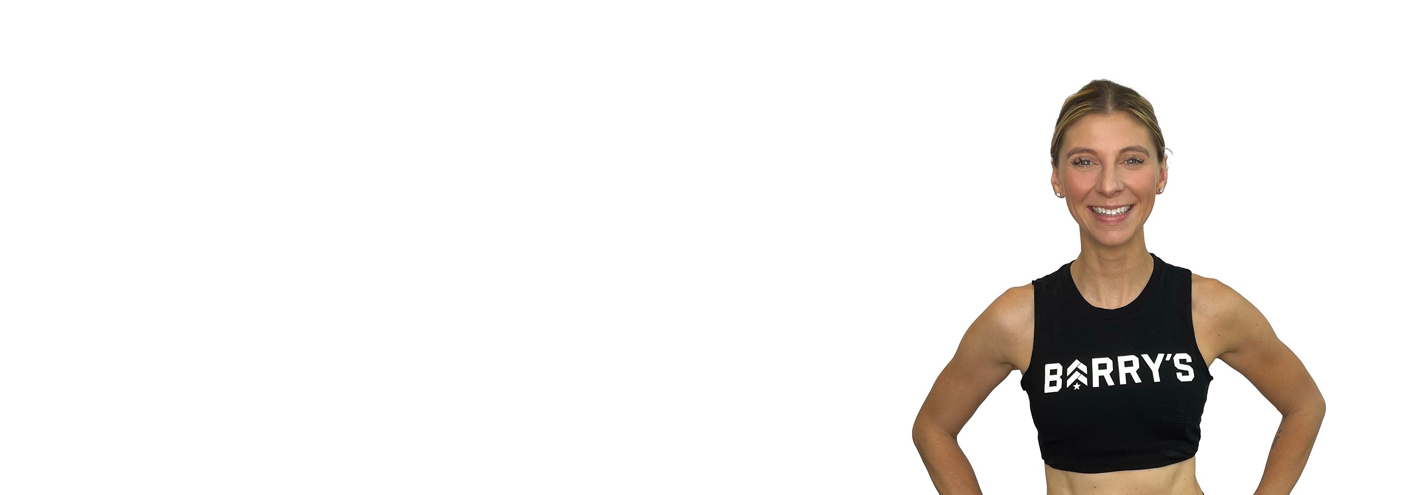 Barry’s instructor wearing a black top standing confidently smiling against a white background