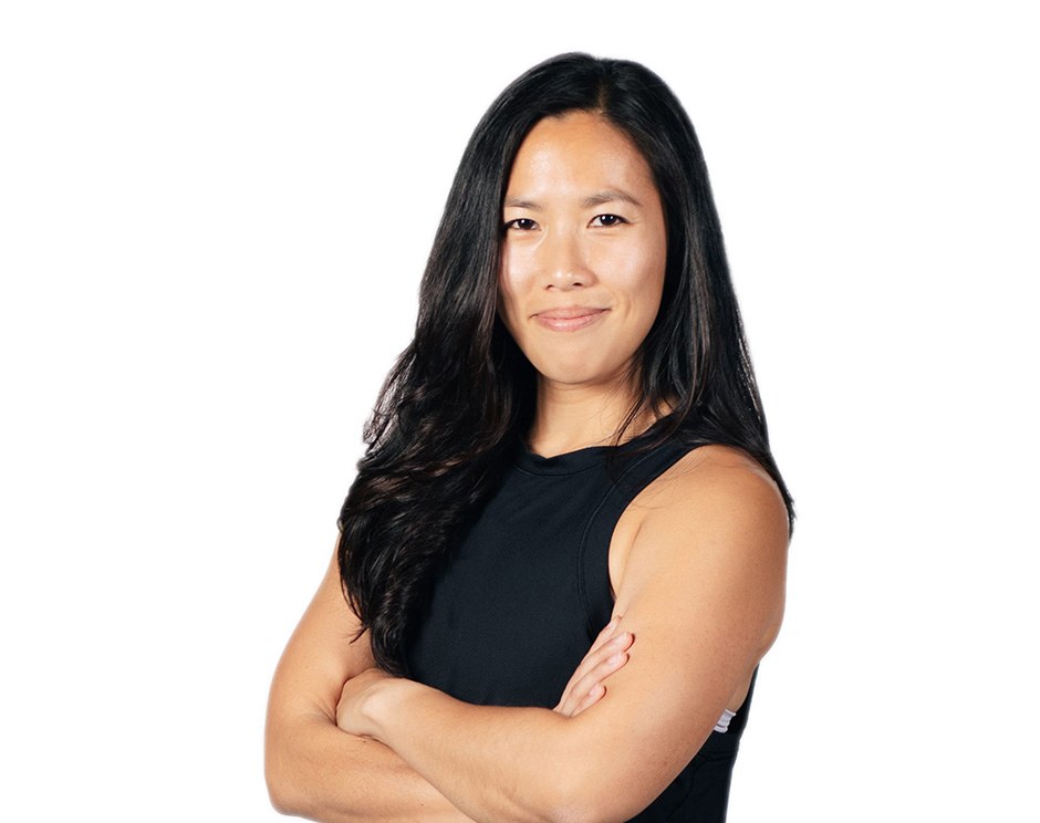 Barry's instructor standing confidently with arms crossed in front, wearing a black tank top against a white background, ready for the next workout challenge.