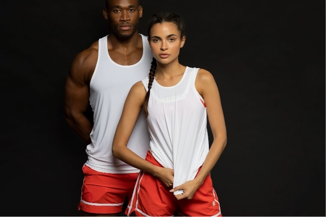 Hombre y mujer modelando con la camiseta sin mangas blanca y los pantalones cortos rojos de Barry