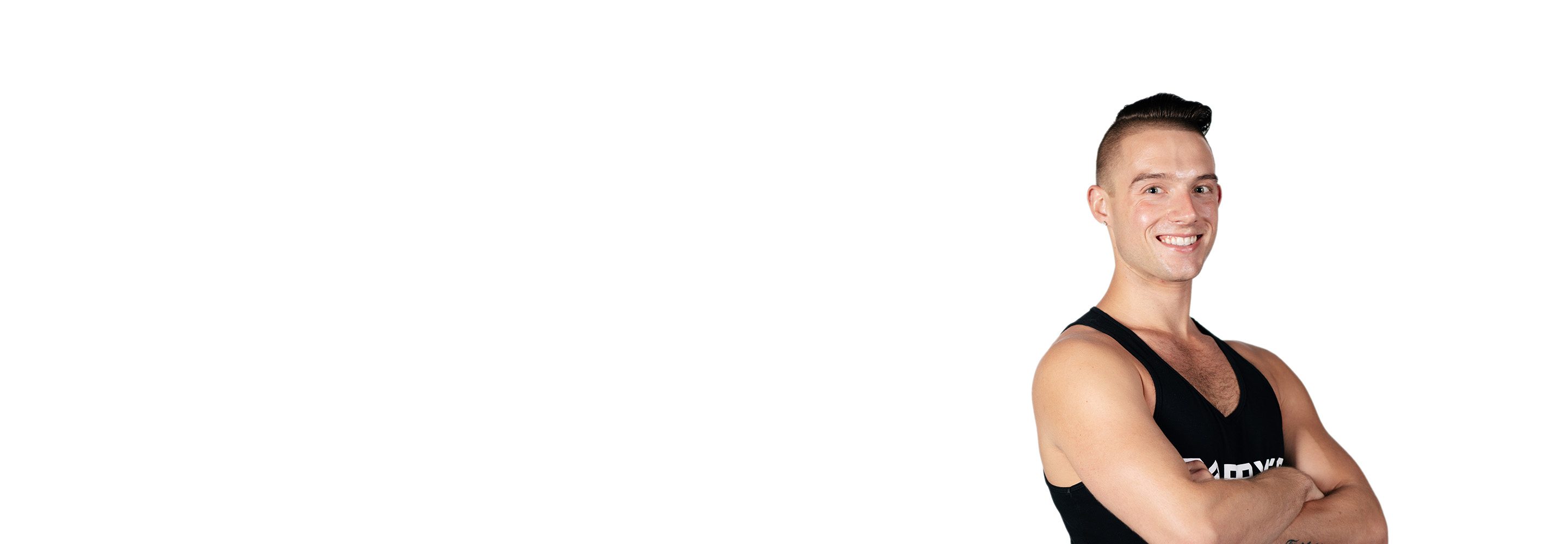 El instructor de Barry aparece de pie, con confianza, vistiendo una camiseta negra sobre un fondo blanco.