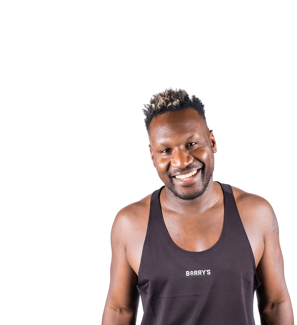 Barrys instruktör iklädd en svart topp står självsäkert och ler mot en vit bakgrund