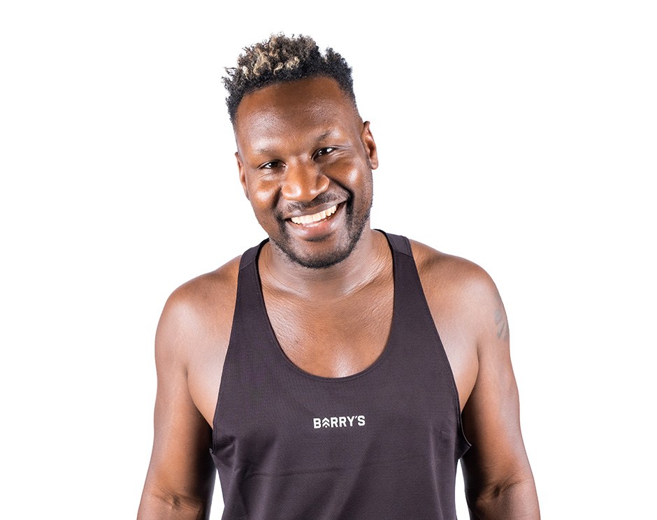 Barry’s instructor wearing a black top standing confidently smiling against a white background