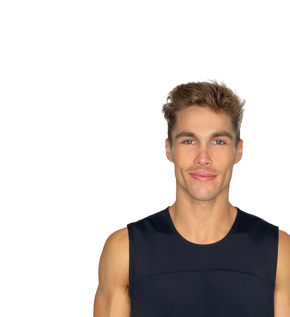 Barry's instructor standing confidently with arms by his side, wearing a black tank top against a white background, ready for the next workout challenge.