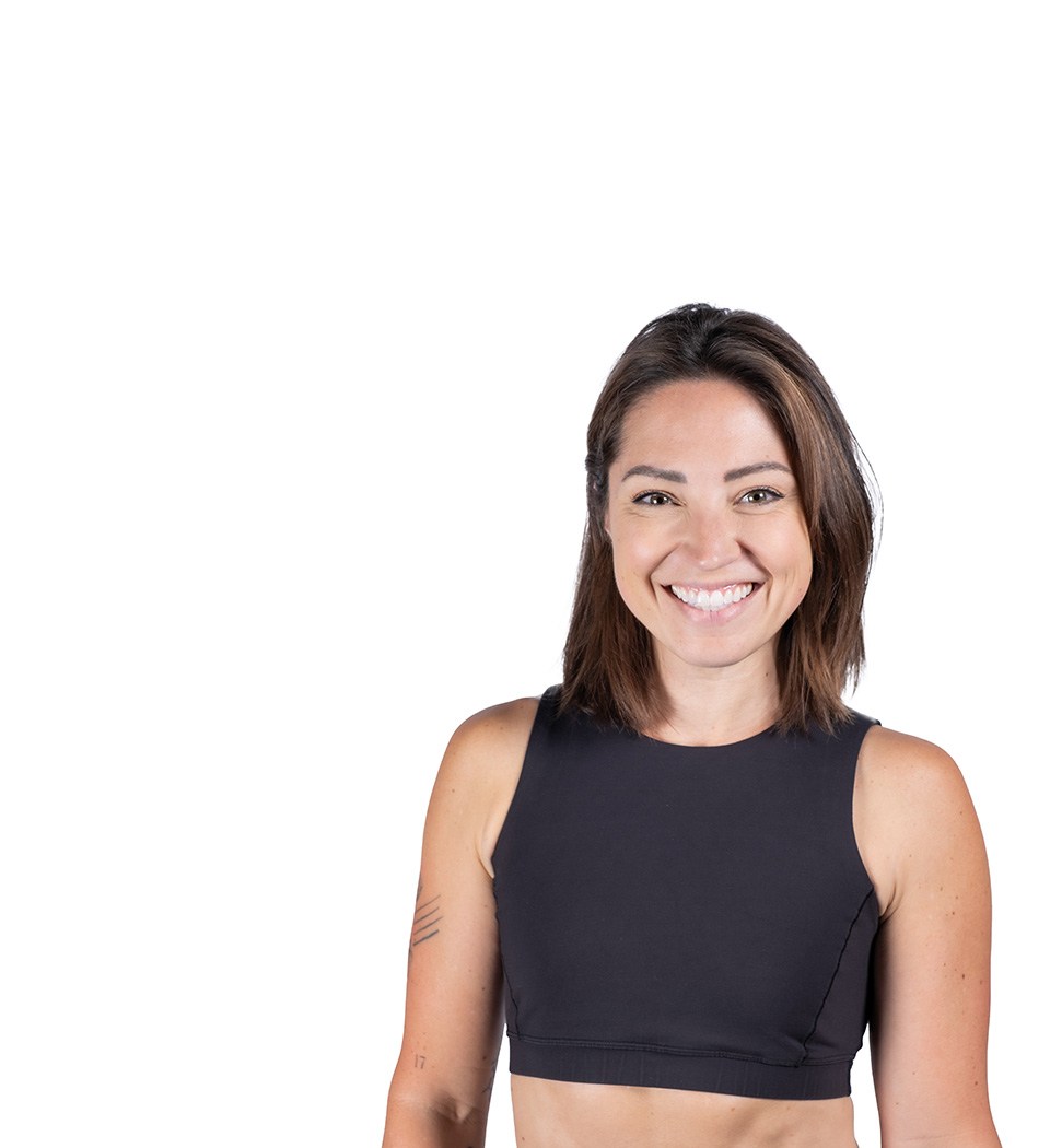 Barry’s instructor wearing a black top standing confidently smiling against a white background