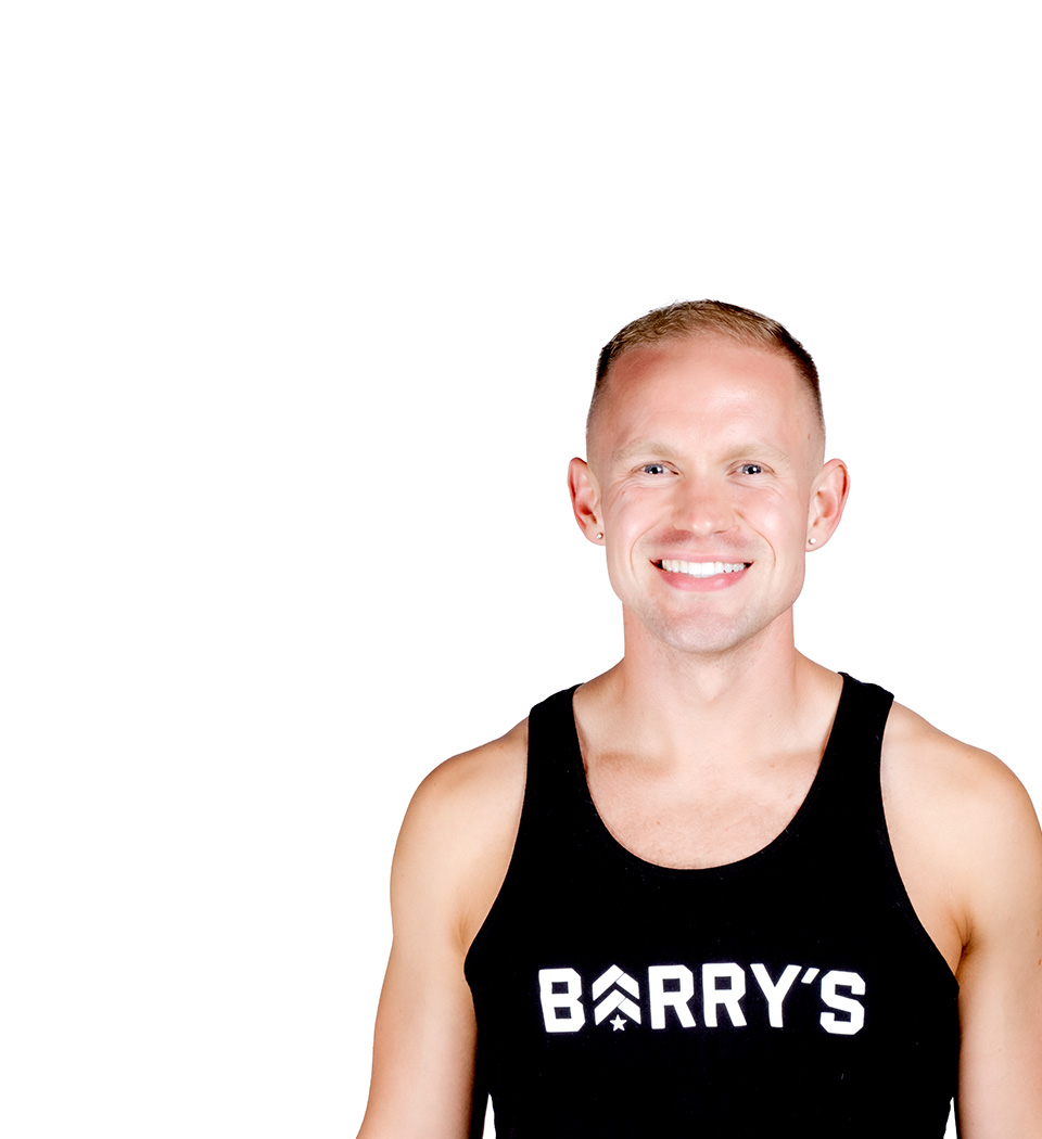 Barry’s instructor wearing a black top standing confidently smiling against a white background