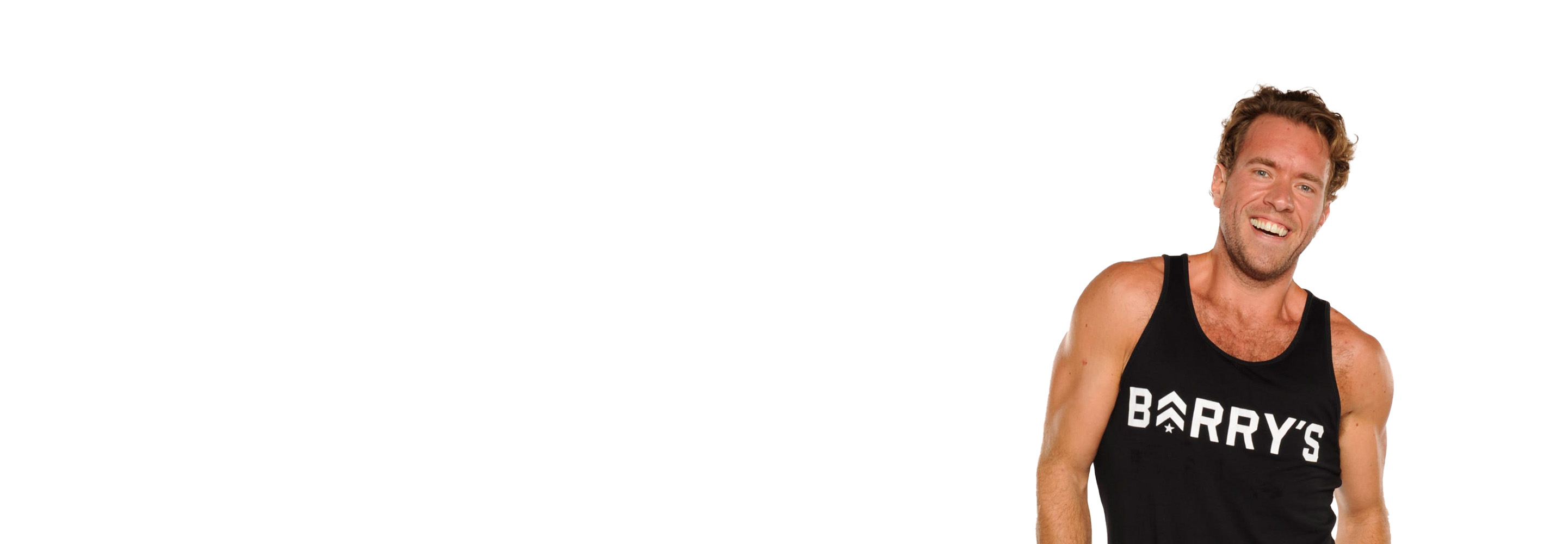 Barry’s instructor wearing a black top standing confidently smiling against a white background