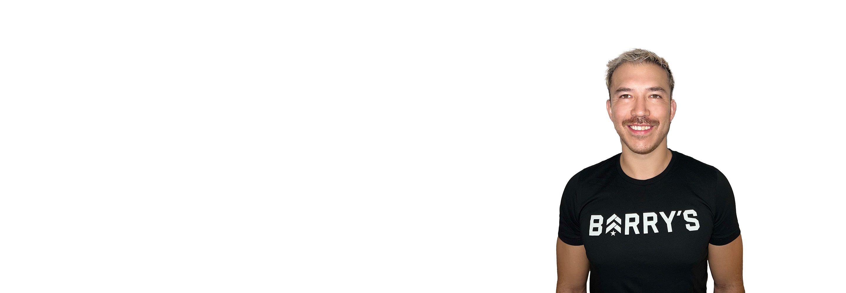 Barry’s instructor wearing a black top standing confidently smiling against a white background