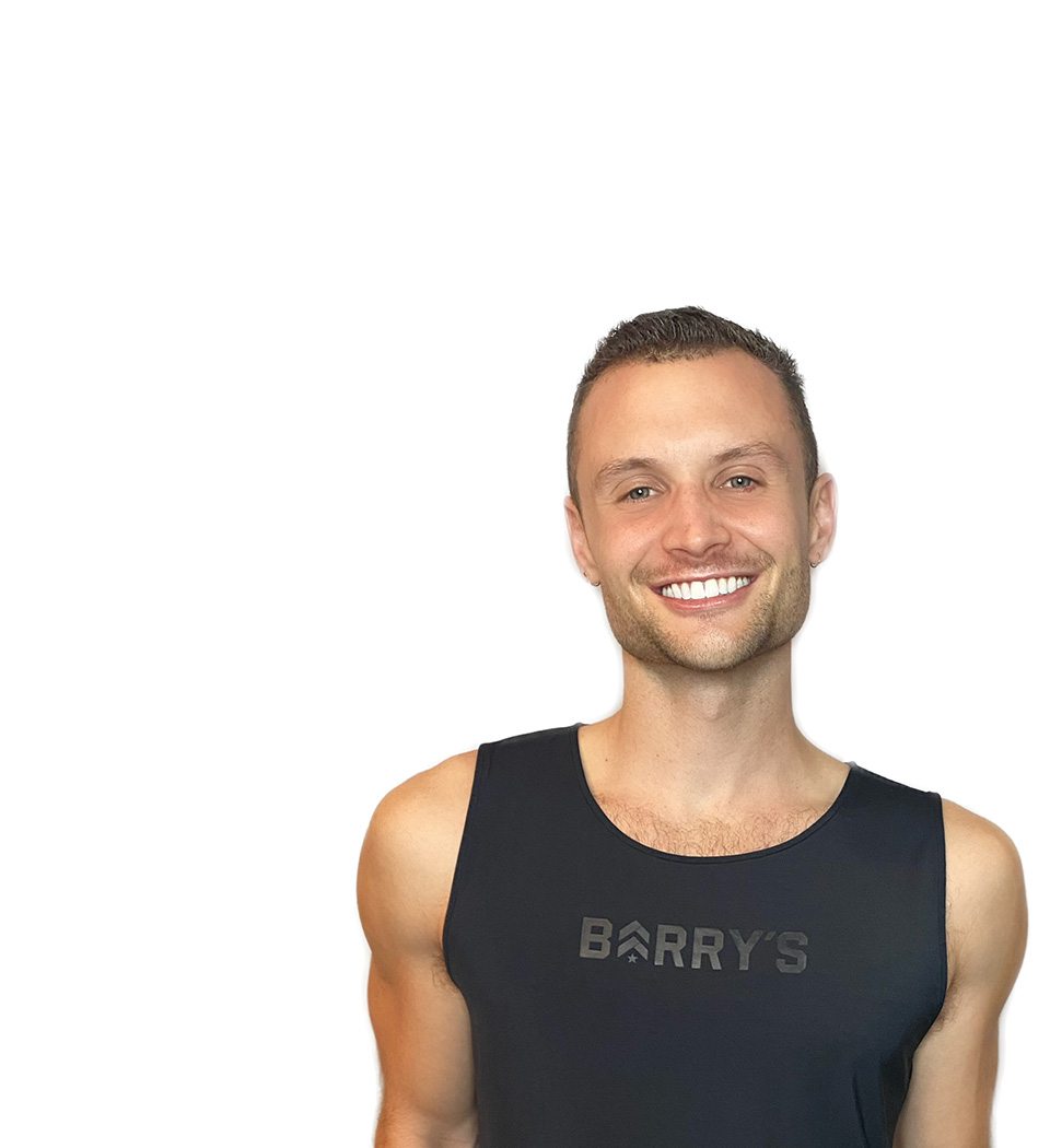 Barry’s instructor wearing a black top standing confidently smiling against a white background