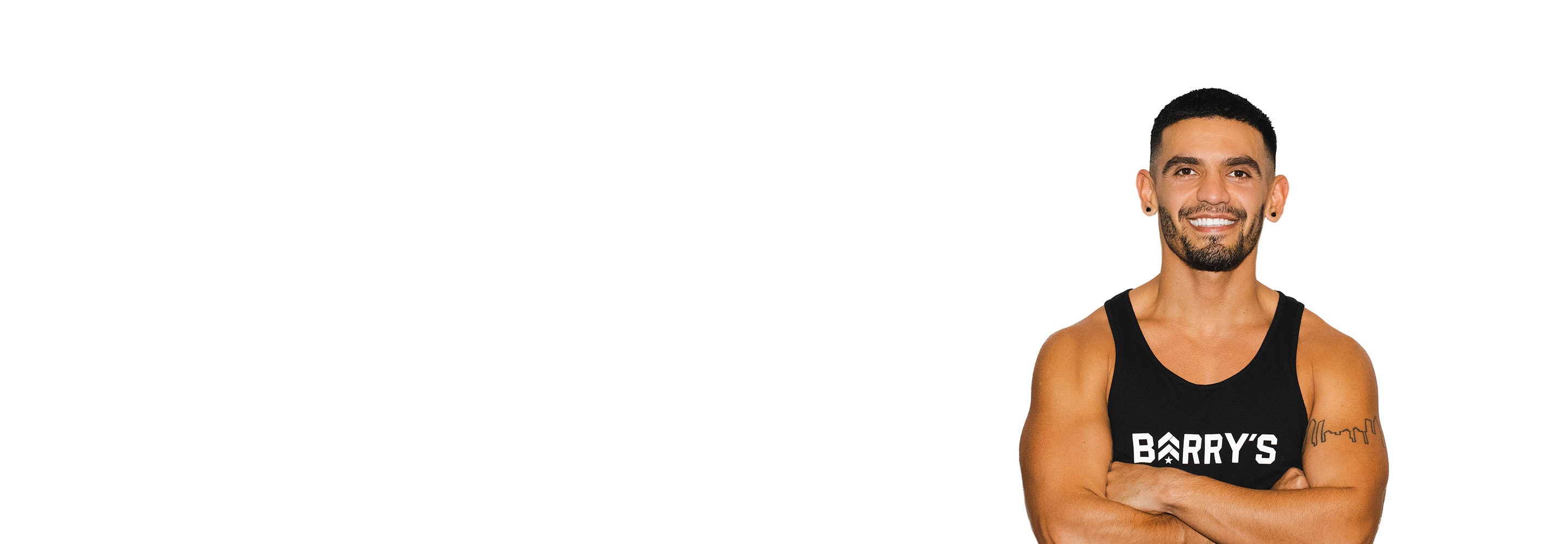 Barry’s instructor wearing a black top standing confidently smiling against a white background