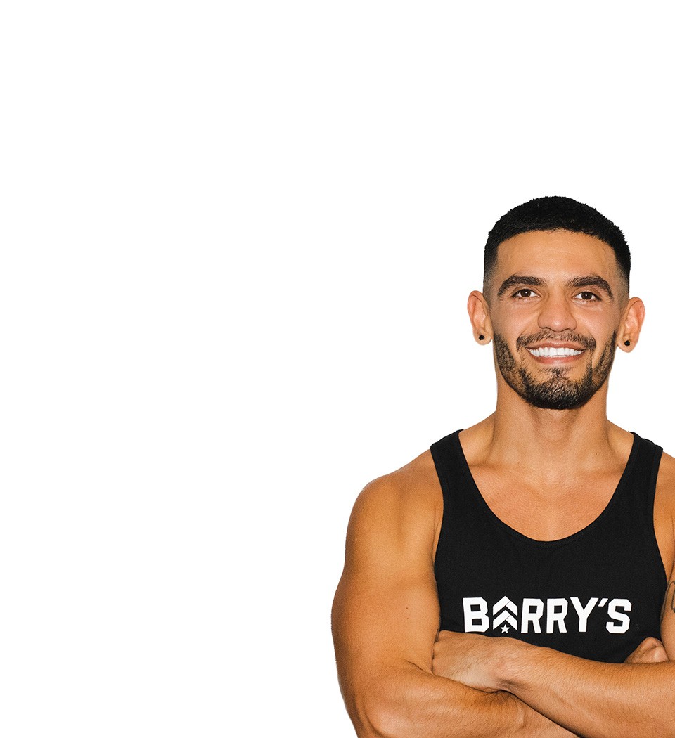 Barry’s instructor wearing a black top standing confidently smiling against a white background