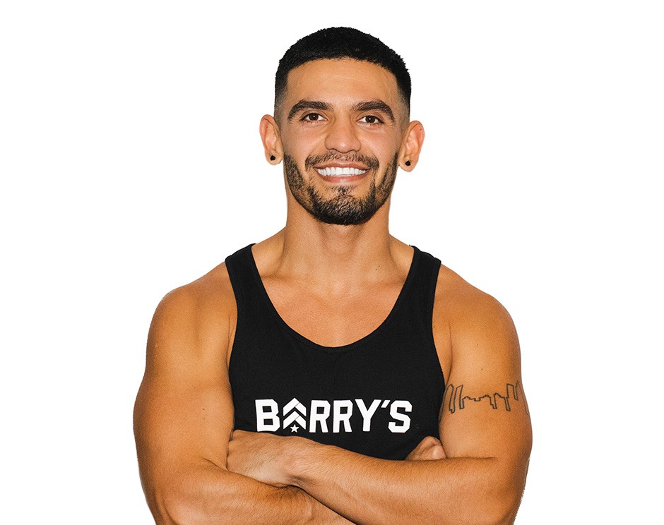 Barry’s instructor wearing a black top standing confidently smiling against a white background