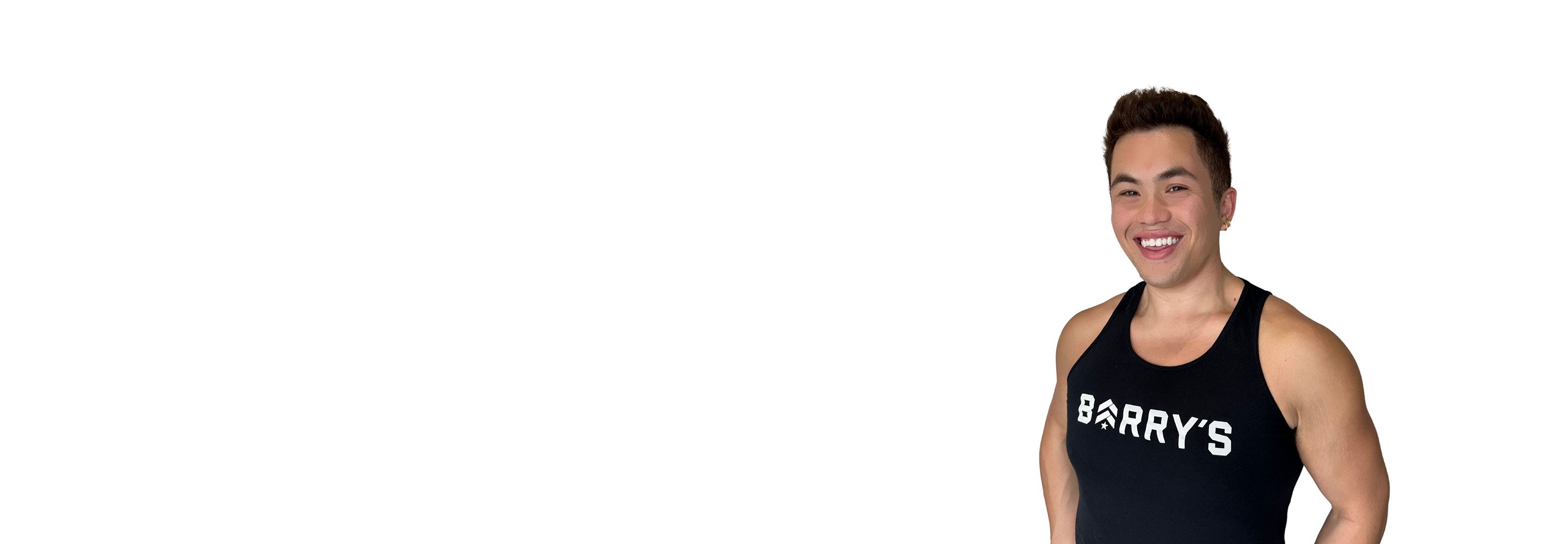 El instructor de Barry aparece de pie, con confianza, vistiendo una camiseta negra sobre un fondo blanco.