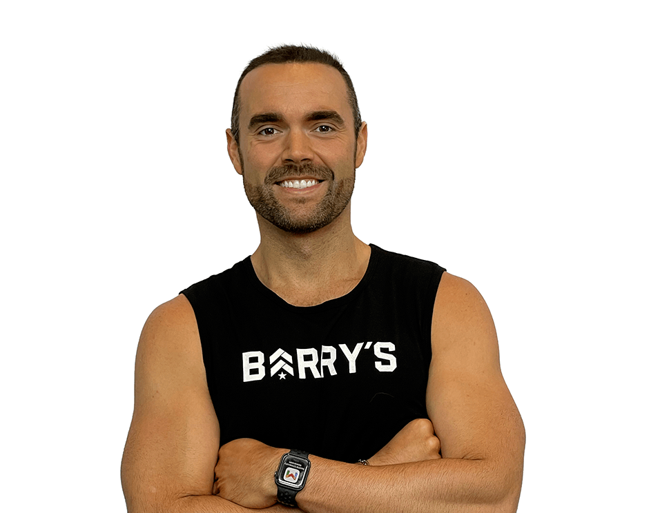 Barry’s instructor wearing a black top standing confidently smiling against a white background