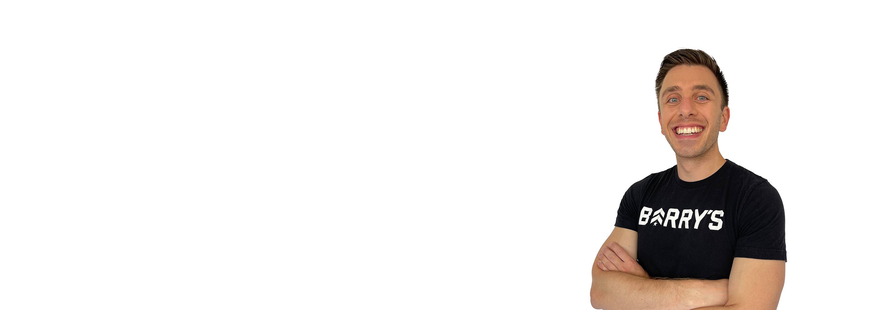 مدرب باري يقف بثقة مرتديًا قميصًا أسود على خلفية بيضاء.
