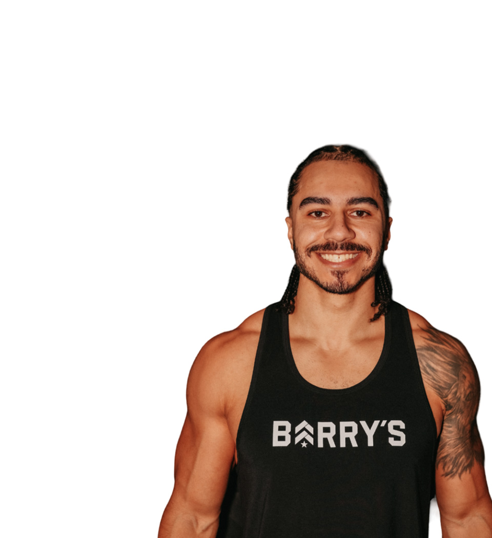Barry’s instructor wearing a black top standing confidently smiling against a white background