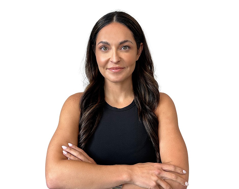 Barry’s instructor wearing a black top standing confidently smiling against a white background