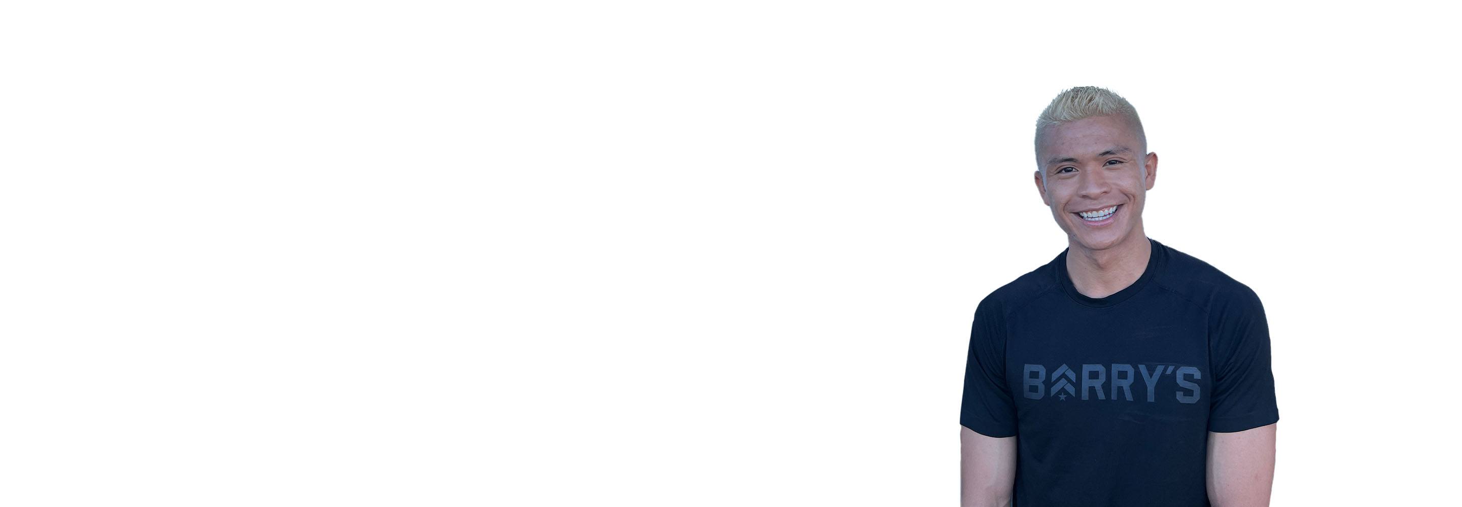 El instructor de Barry se mantiene firme, vistiendo una camiseta negra sobre un fondo blanco, listo para el próximo desafío de entrenamiento.