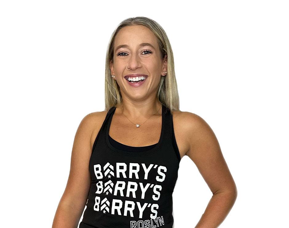 Barry’s instructor wearing a black top standing confidently smiling against a white background