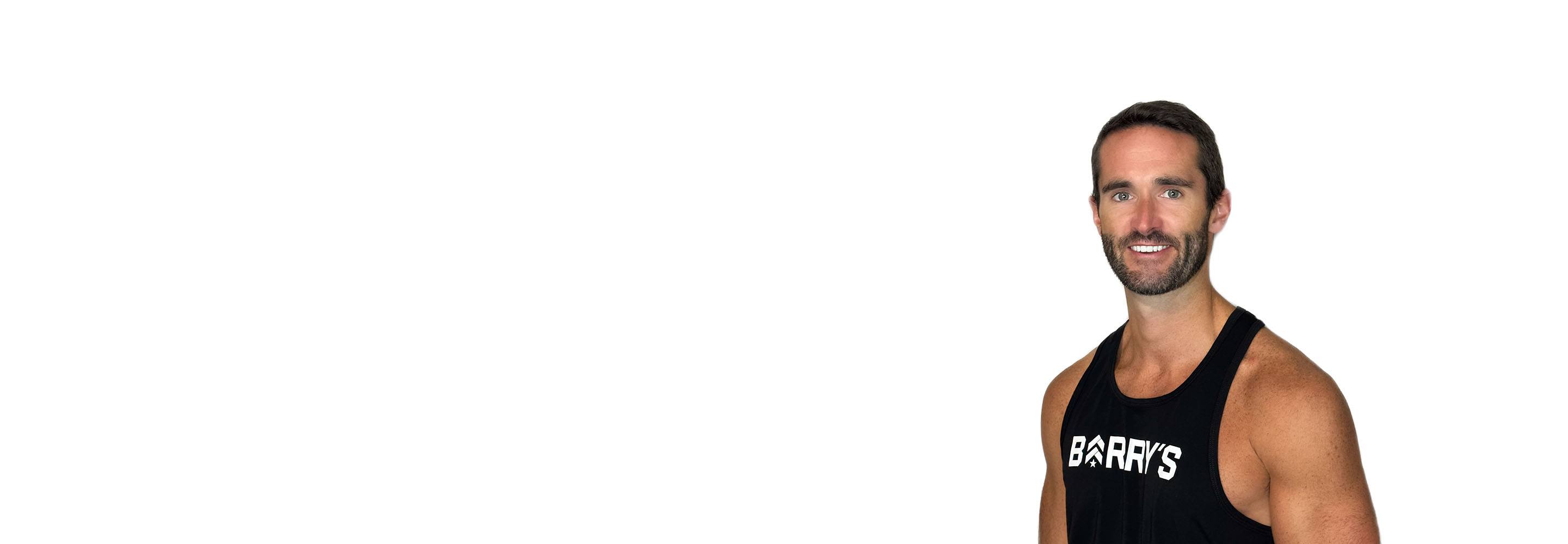 Barry’s instructor wearing a black top standing confidently smiling against a white background