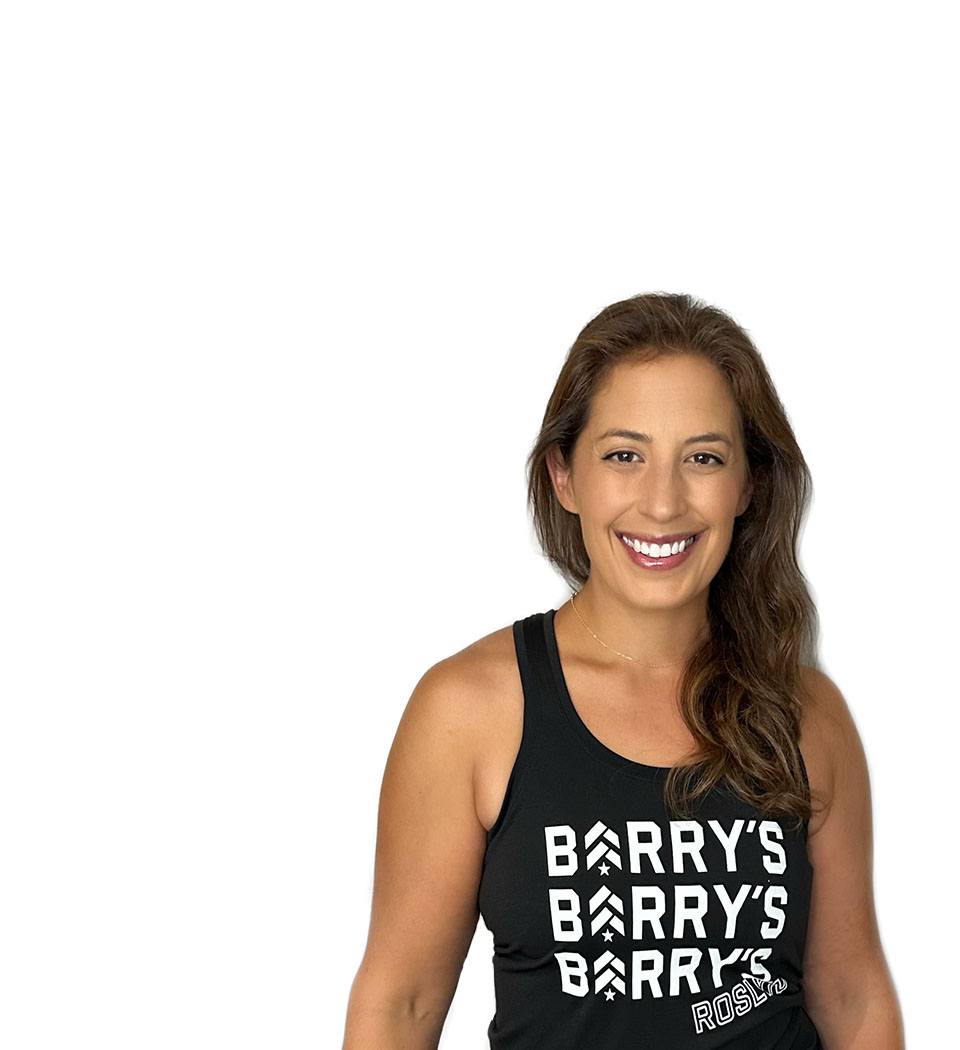 Barry’s instructor wearing a black top standing confidently smiling against a white background