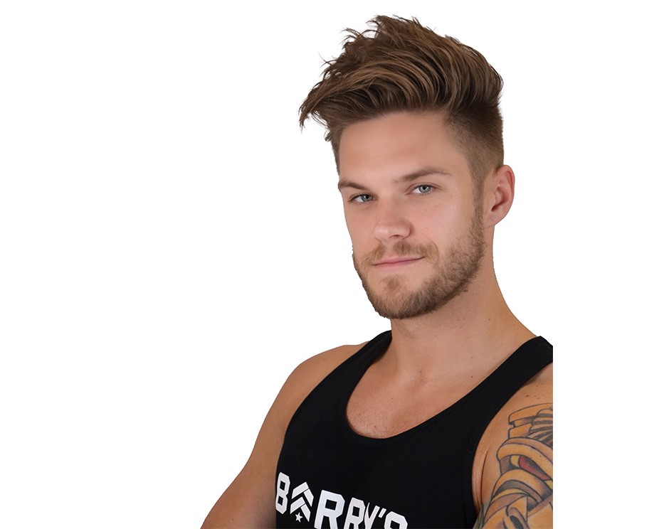 Barry’s instructor wearing a black top standing confidently smiling against a white background