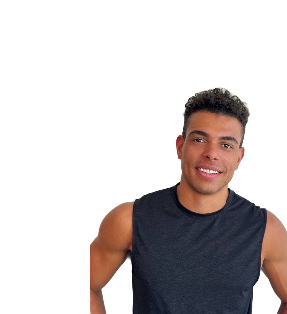 Barry’s instructor wearing a black top standing confidently smiling against a white background