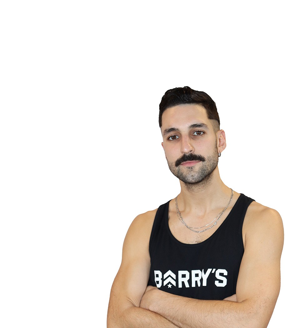 Barry’s instructor wearing a black top standing confidently smiling against a white background