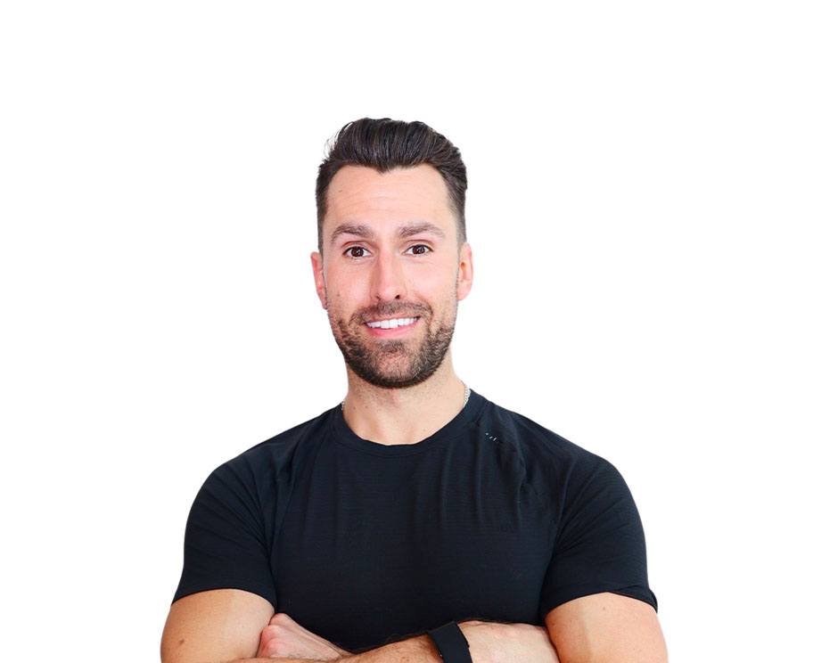 Barry’s instructor wearing a black top standing confidently smiling against a white background
