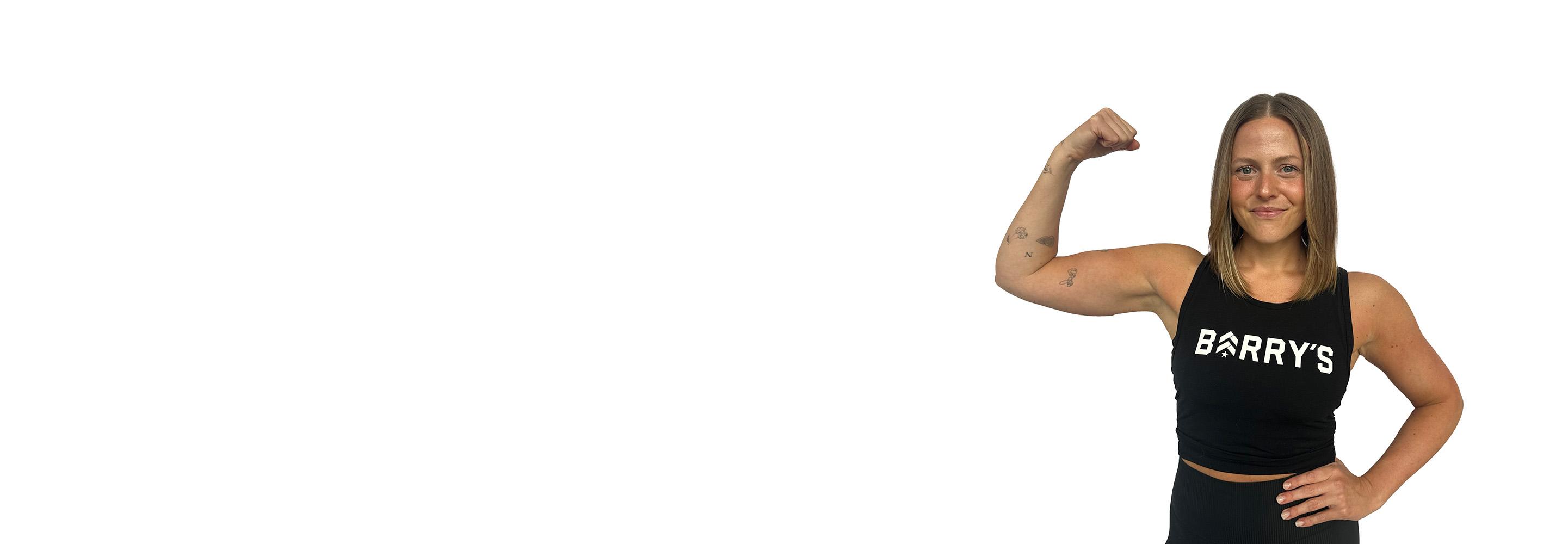 Barry’s instructor wearing a black top standing confidently smiling against a white background