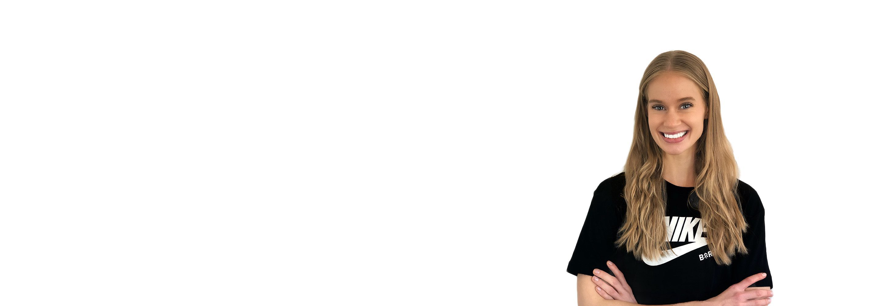 Barry’s instructor wearing a black top standing confidently smiling against a white background