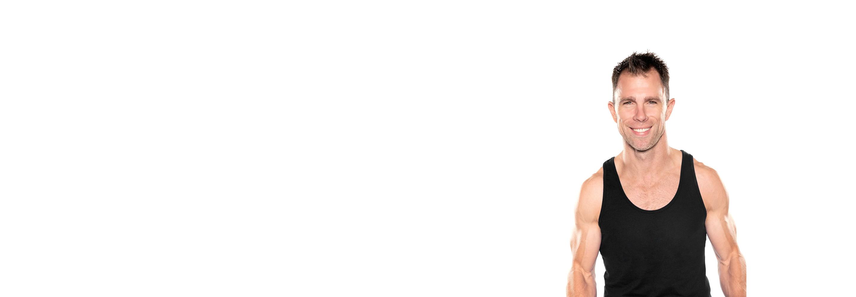 El instructor de Barry aparece de pie, con confianza, vistiendo una camiseta negra sobre un fondo blanco.