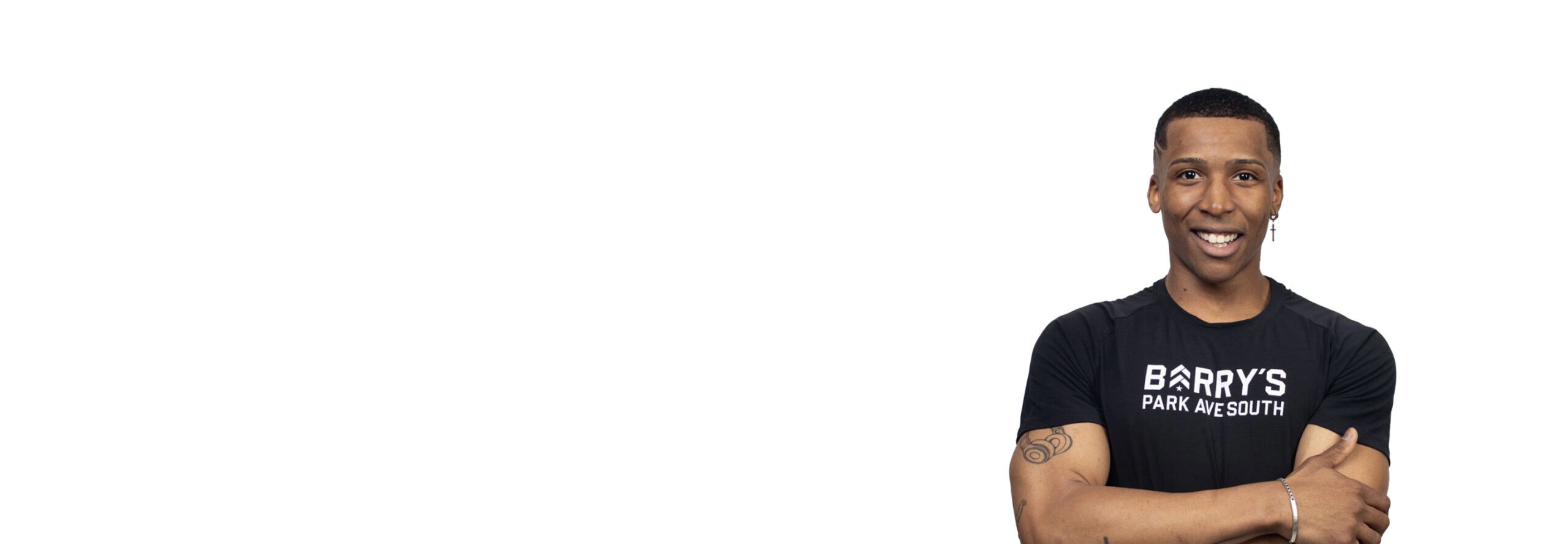 Barry’s instructor wearing a black top standing confidently smiling against a white background