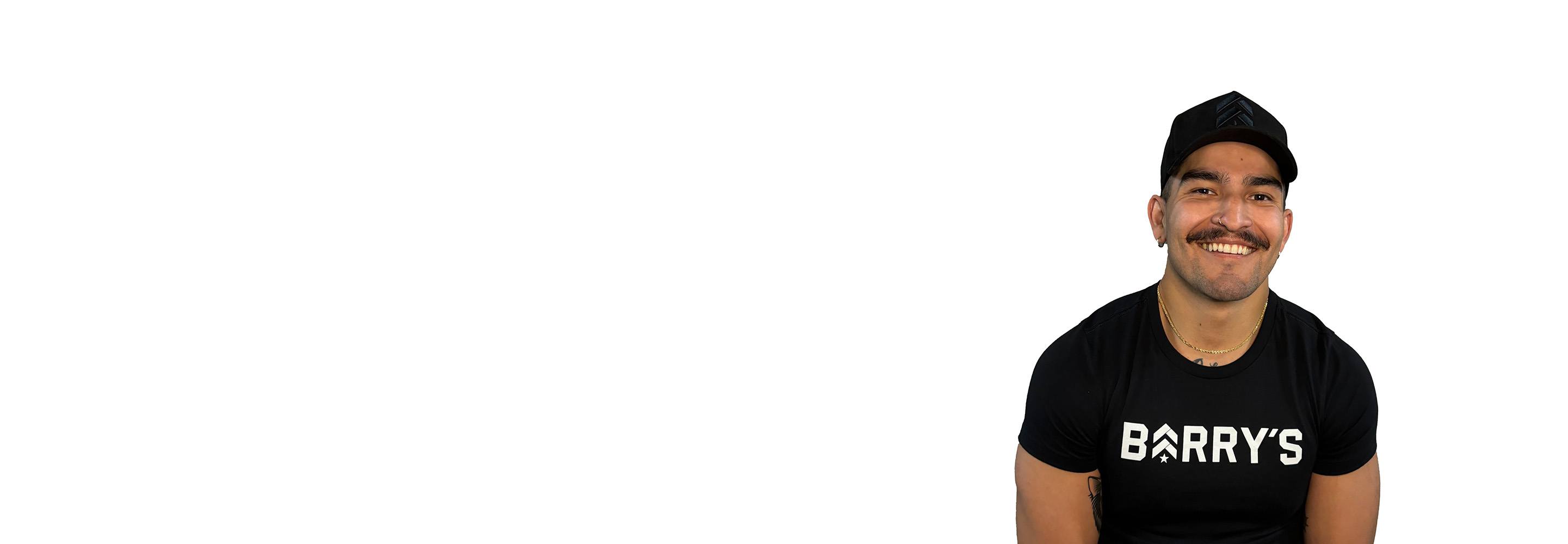 Barry's instructor standing confidently, wearing a black tank top against a white background, ready for the next workout challenge.