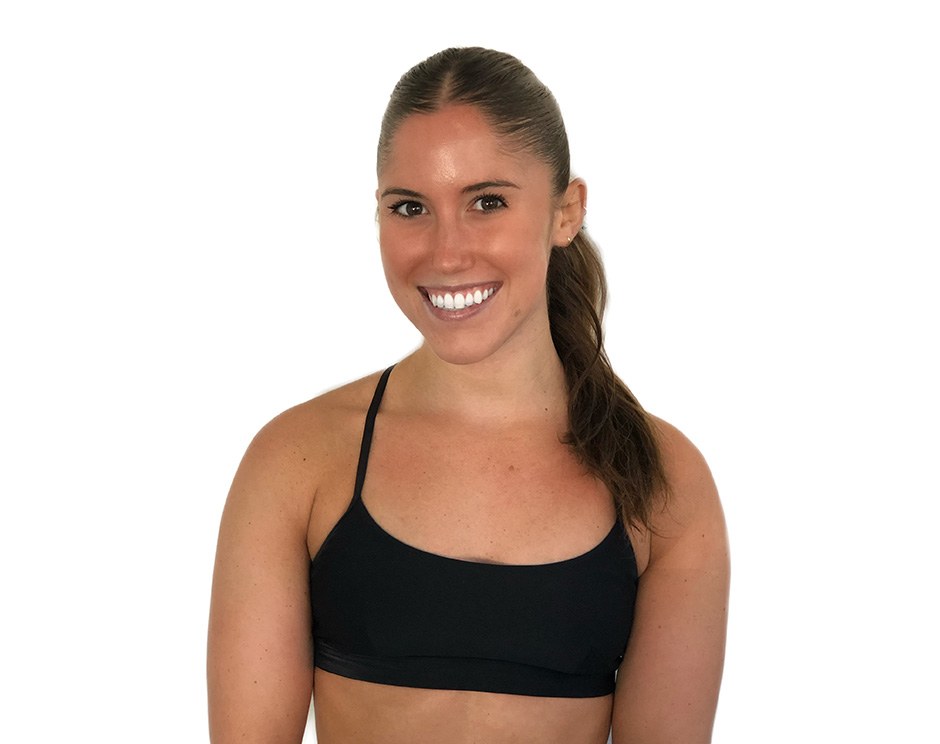 Barry’s instructor wearing a black top standing confidently smiling against a white background