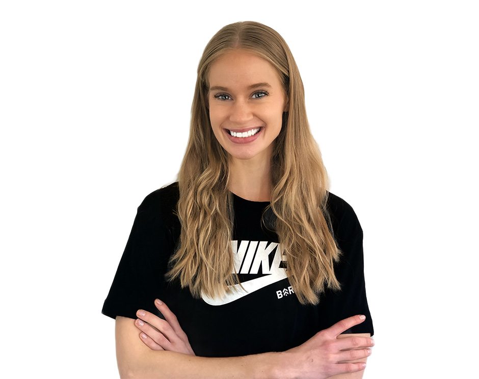 Barry’s instructor wearing a black top standing confidently smiling against a white background