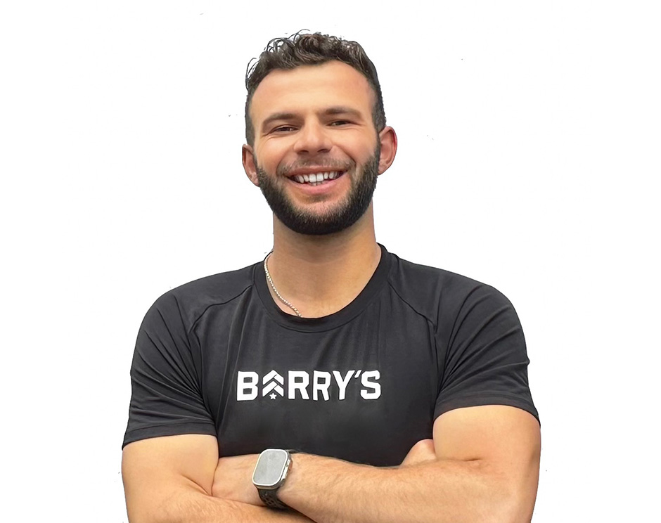 Barry's instructor standing confidently wearing a black tank top against a white background, ready for the next workout challenge.