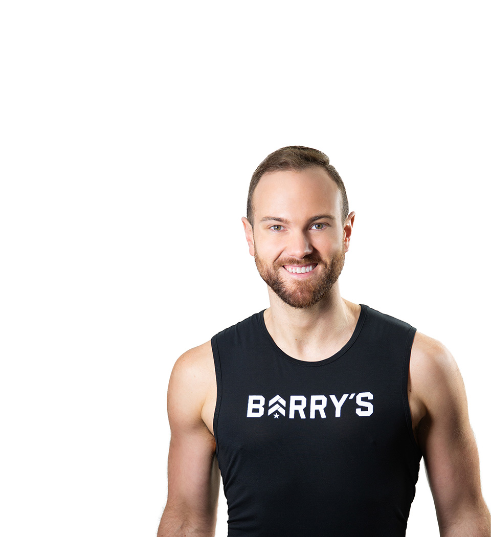 Barry’s instructor wearing a black top standing confidently smiling against a white background