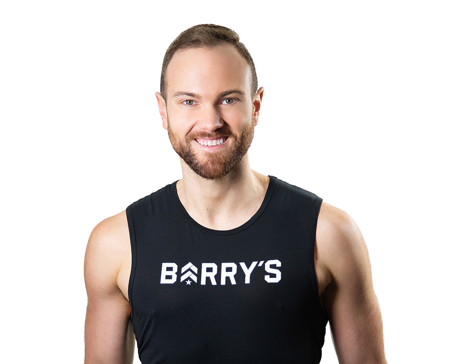 Barry’s instructor wearing a black top standing confidently smiling against a white background