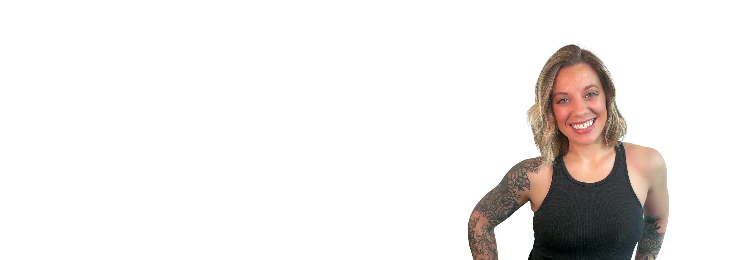 Barry’s instructor wearing a black top standing confidently smiling against a white background