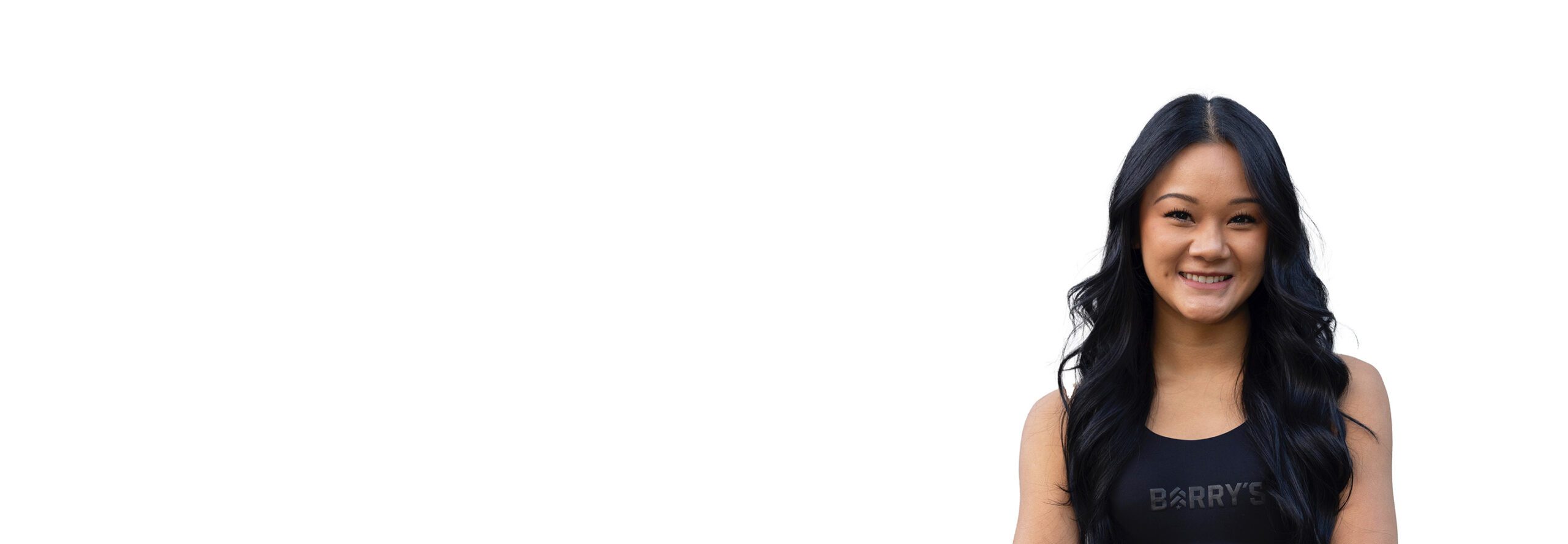 L'instructeur de Savannah Le Barry portant un haut noir se tient debout et sourit avec confiance sur un fond blanc