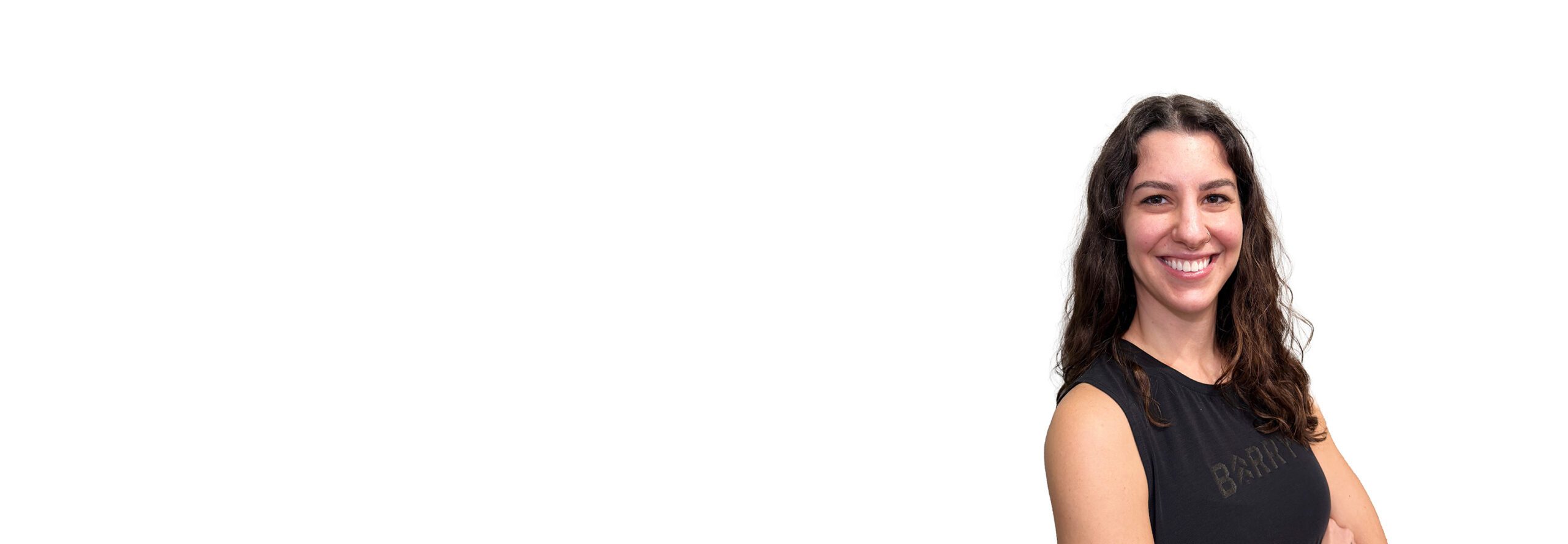 Barry’s instructor wearing a black top standing confidently smiling against a white background